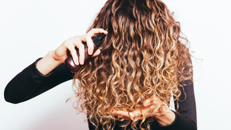 Hair Growth Spray being sprayed on curly wavy hair