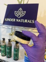 Batana Hair Oil in jar being held with Kinder Naturals sign in background